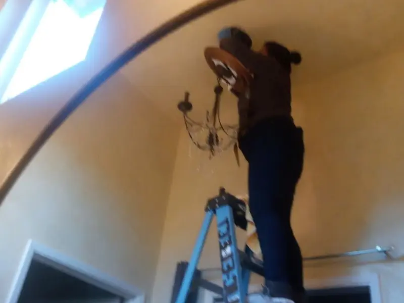 Electrician installing a chandelier in a Williamston residence